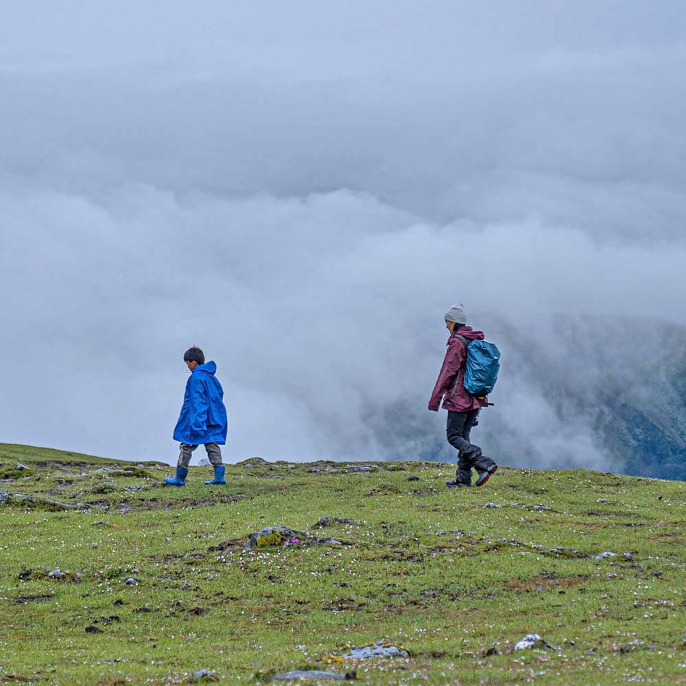 Trekkers walking a ridge into the clouds in Bhutan